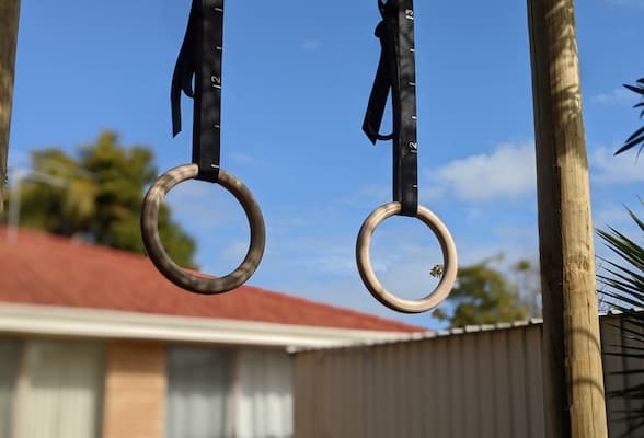 Rep Fitness wooden gymnastic rings hanging from pull-up bar