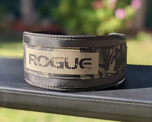 Rogue USA nylon lifting belt on a weight bench in a backyard