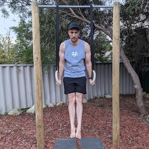 man doing push-up support hold on gymnastic rngs in back garden