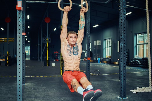 Man on gymnastic rings showing benefits to physique