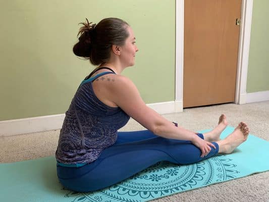 Author doing seated forward fold yoga stretch to improve flexibility