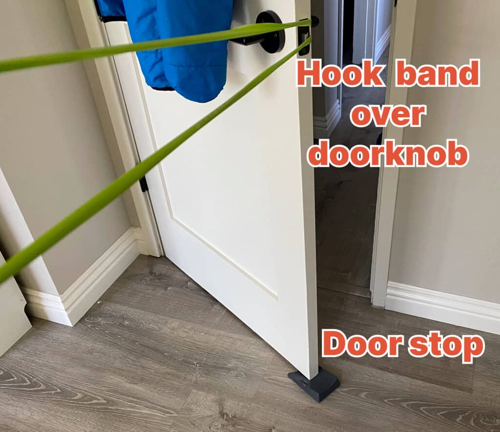 Exercise band attached to a doorknob. The door is secured with an extra-large door stop