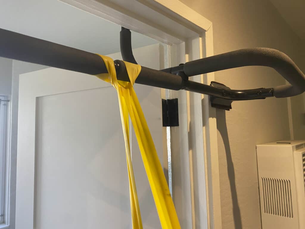 Exercise band attached to a pull-up bar in a doorway.